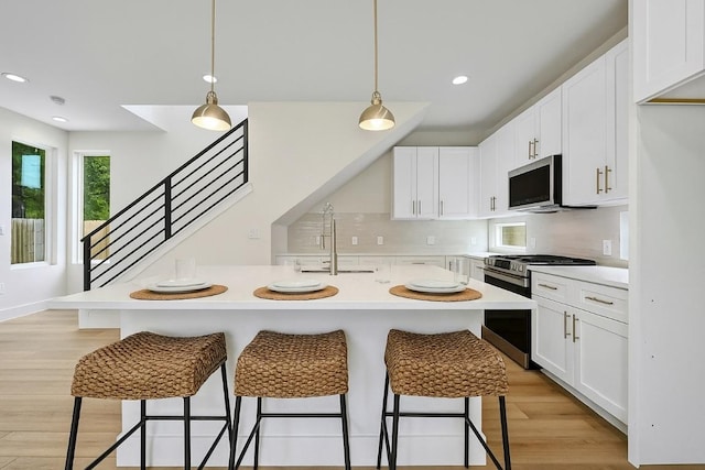 9104 Georgian Dr, Austin, TX 78753 - kitchen featuring appliances with stainless steel finishes, a breakfast bar, light countertops, white cabinets, and recessed lighting