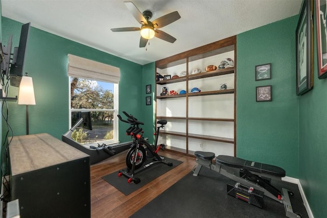 exercise area featuring wood-type flooring, a textured ceiling, and ceiling fan