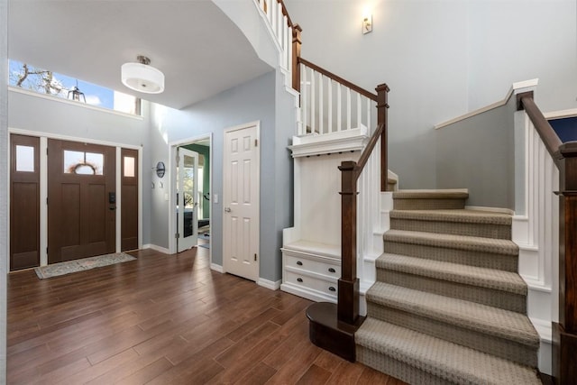 foyer entrance featuring a towering ceiling and dark hardwood / wood-style floors