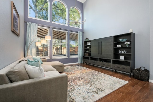 living area featuring dark wood-type flooring, a wealth of natural light, a towering ceiling, and baseboards