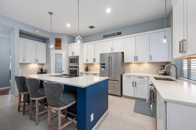 kitchen with a center island, white cabinets, sink, appliances with stainless steel finishes, and decorative light fixtures