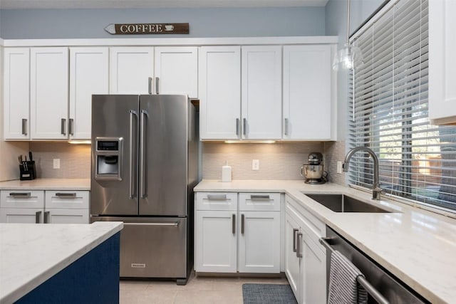 kitchen featuring light tile patterned floors, a sink, white cabinetry, stainless steel appliances, and decorative backsplash