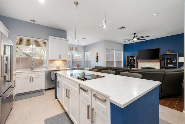 kitchen featuring a center island, ceiling fan, white cabinets, and stainless steel appliances