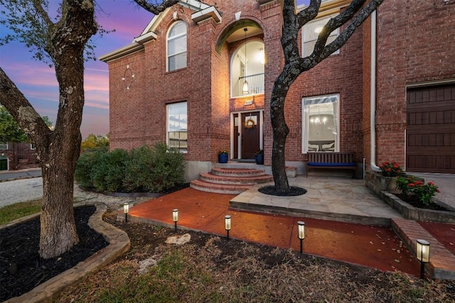 exterior entry at dusk featuring a garage