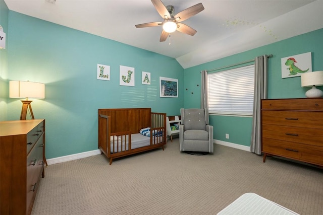 bedroom featuring ceiling fan, light colored carpet, a nursery area, and lofted ceiling