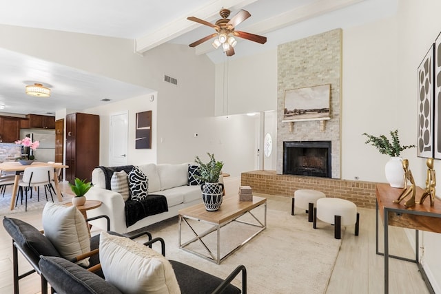 living room with ceiling fan, beamed ceiling, high vaulted ceiling, a fireplace, and light wood-type flooring