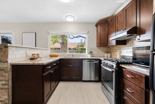 kitchen featuring sink, stainless steel appliances, light stone counters, decorative backsplash, and dark brown cabinets