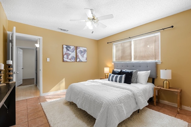 tiled bedroom with ceiling fan and a textured ceiling