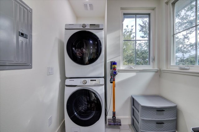 laundry area with electric panel and stacked washing maching and dryer