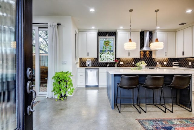 kitchen featuring white cabinetry, dishwasher, sink, hanging light fixtures, and wall chimney exhaust hood