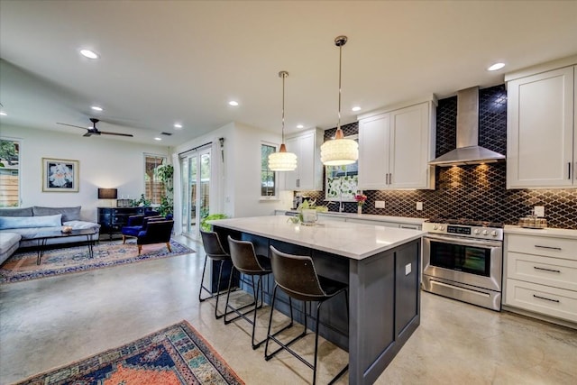 kitchen with a kitchen island, decorative light fixtures, white cabinets, high end range, and wall chimney exhaust hood