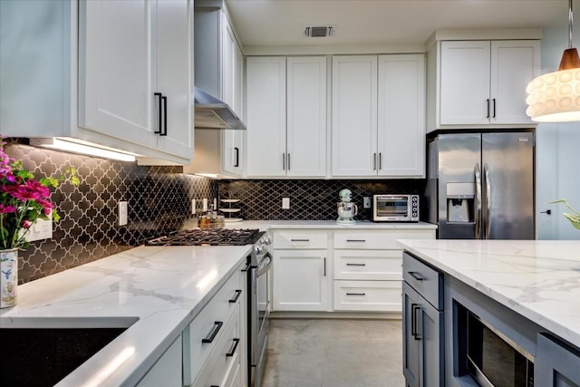 kitchen featuring appliances with stainless steel finishes, decorative light fixtures, tasteful backsplash, white cabinetry, and light stone countertops