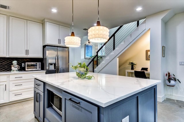 kitchen featuring white cabinetry, light stone counters, hanging light fixtures, stainless steel appliances, and decorative backsplash