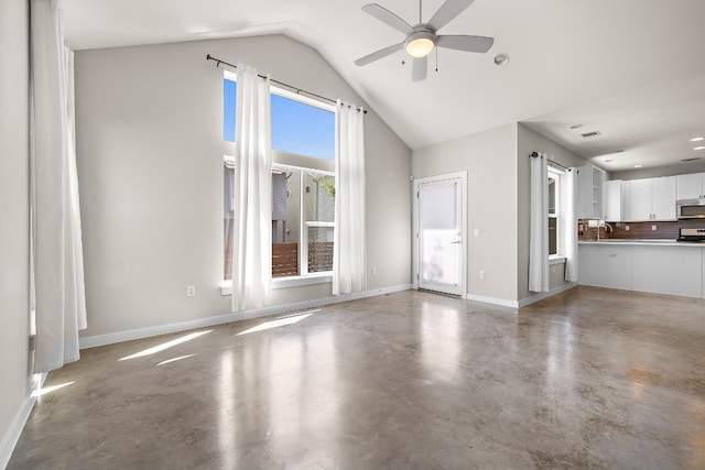 unfurnished living room with ceiling fan, lofted ceiling, sink, and concrete floors