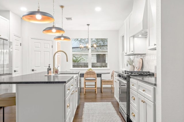 kitchen with stainless steel stove, white cabinetry, and an island with sink