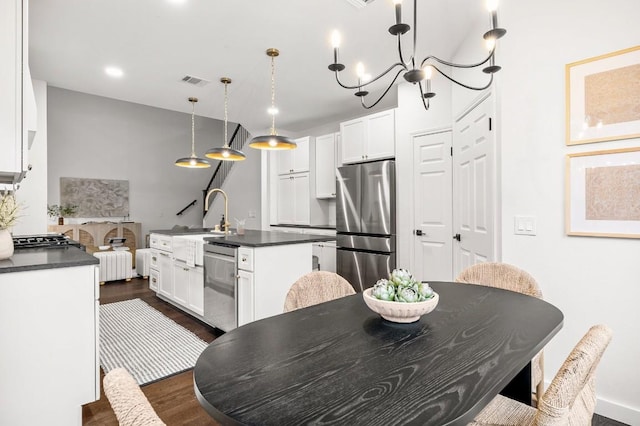 kitchen with decorative light fixtures, dark hardwood / wood-style floors, white cabinetry, and appliances with stainless steel finishes