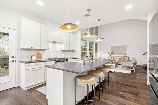 kitchen with a center island with sink, decorative light fixtures, dark hardwood / wood-style flooring, and white cabinets