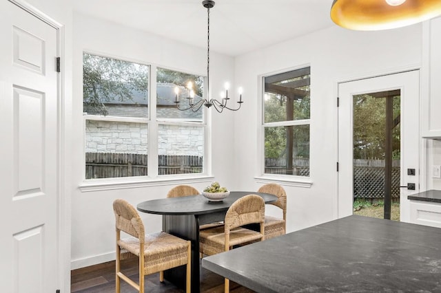 dining area with dark hardwood / wood-style floors and an inviting chandelier