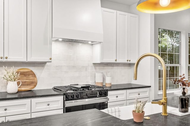 kitchen with black gas range, backsplash, white cabinets, and custom exhaust hood