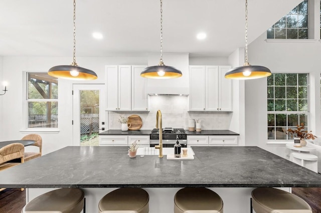 kitchen with decorative backsplash, white cabinetry, and an island with sink