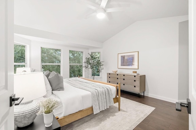 bedroom featuring ceiling fan, dark hardwood / wood-style floors, vaulted ceiling, and multiple windows