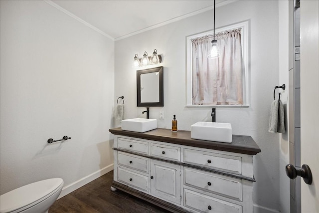 bathroom with crown molding, baseboards, a sink, and wood finished floors