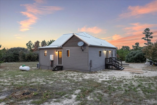 back of house at dusk featuring entry steps and metal roof