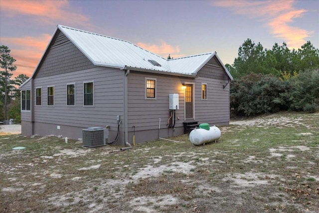 back of house at dusk with metal roof and cooling unit