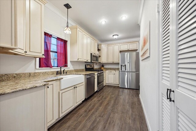 kitchen with stainless steel appliances, cream cabinetry, a sink, and ornamental molding