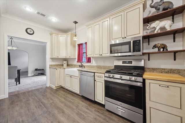 kitchen featuring arched walkways, visible vents, cream cabinets, stainless steel appliances, and a sink