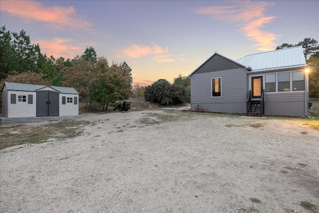 exterior space featuring a storage shed, metal roof, an outbuilding, and entry steps