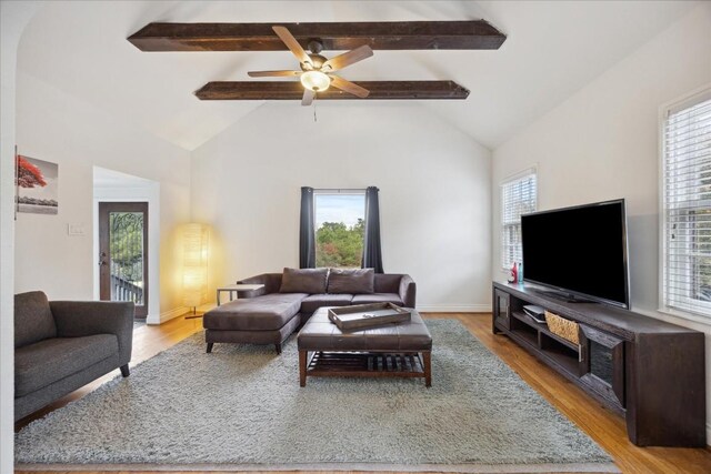 living room featuring beam ceiling, ceiling fan, baseboards, and wood finished floors