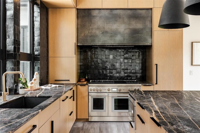 kitchen featuring light brown cabinets, double oven range, sink, hardwood / wood-style flooring, and dark stone countertops