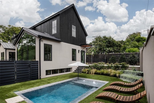 rear view of property featuring a fenced in pool and a lawn