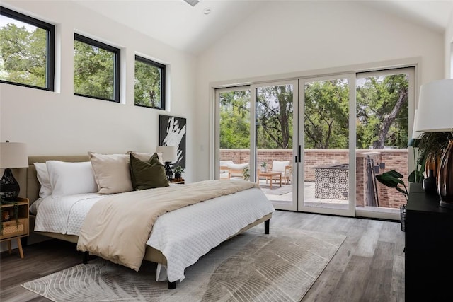 bedroom featuring hardwood / wood-style floors, access to exterior, and high vaulted ceiling