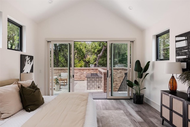 bedroom featuring access to outside, vaulted ceiling, and light wood-type flooring