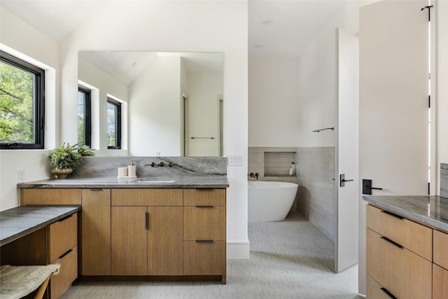 bathroom featuring tile patterned floors, vanity, lofted ceiling, and a washtub