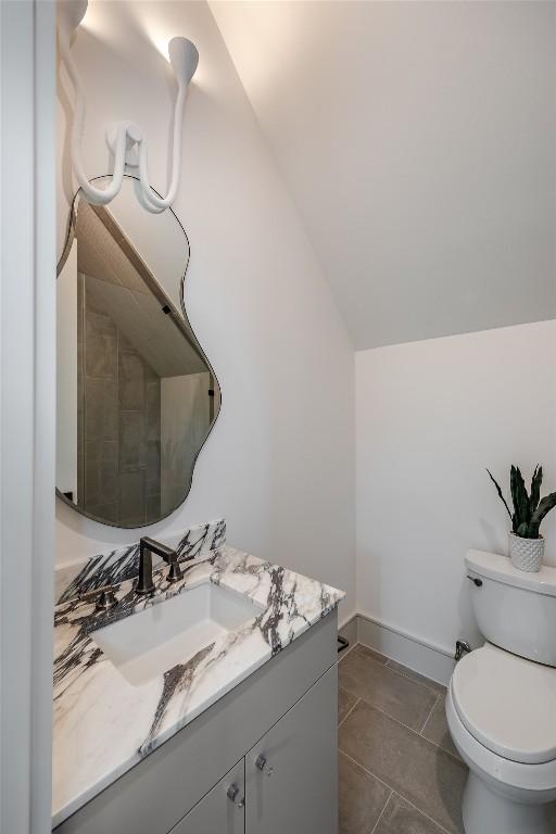 bathroom featuring toilet, vanity, and vaulted ceiling