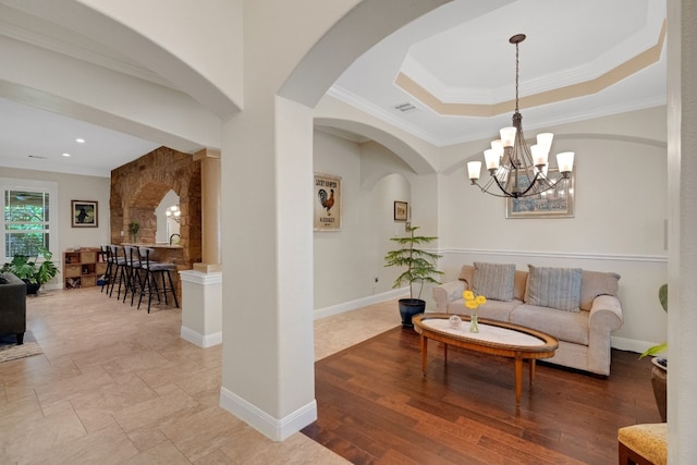 living room with hardwood / wood-style flooring, an inviting chandelier, and ornamental molding