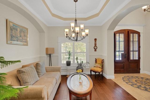 living room featuring dark hardwood / wood-style flooring, ornamental molding, and an inviting chandelier