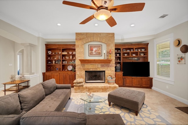 tiled living room featuring a stone fireplace, crown molding, and ceiling fan