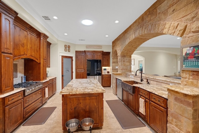 kitchen featuring sink, stainless steel appliances, light stone counters, kitchen peninsula, and a kitchen island