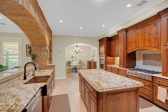 kitchen with a kitchen island, light stone counters, appliances with stainless steel finishes, and tasteful backsplash