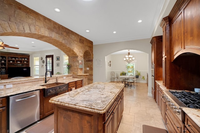 kitchen with light stone countertops, a center island, sink, stainless steel appliances, and ceiling fan with notable chandelier