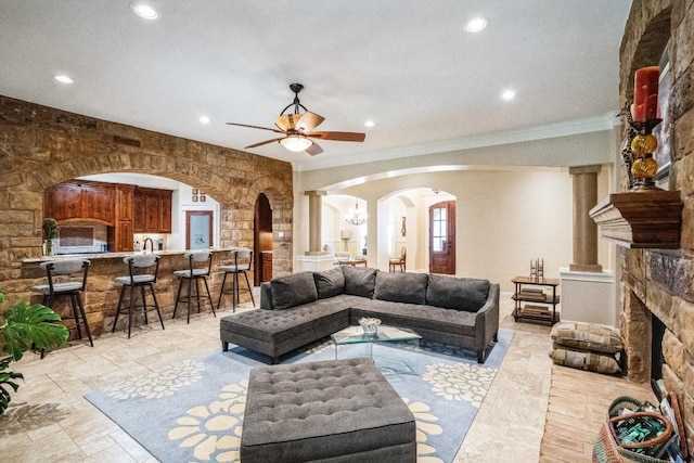 living room featuring a fireplace, decorative columns, ceiling fan, and crown molding