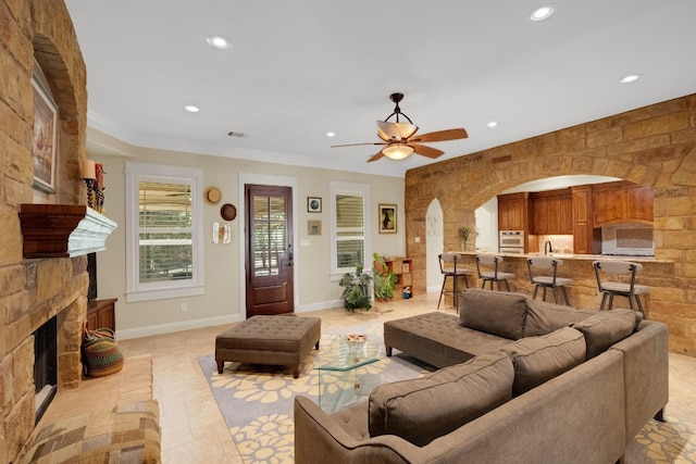 living room with a fireplace, light tile patterned floors, ceiling fan, and ornamental molding