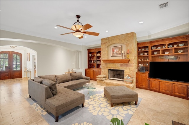 living room with ceiling fan, ornamental molding, a fireplace, and french doors