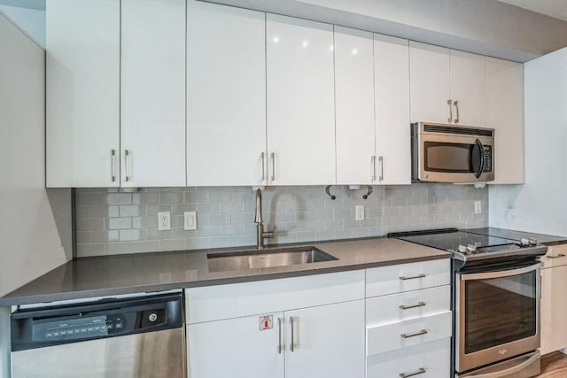 6444 Burnet Rd Unit 305, Austin, TX 78757 - kitchen with appliances with stainless steel finishes, a sink, white cabinetry, tasteful backsplash, and dark countertops
