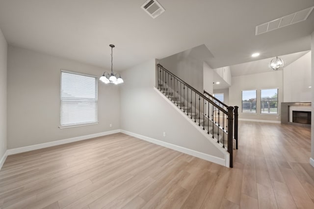 unfurnished room with a notable chandelier and light wood-type flooring