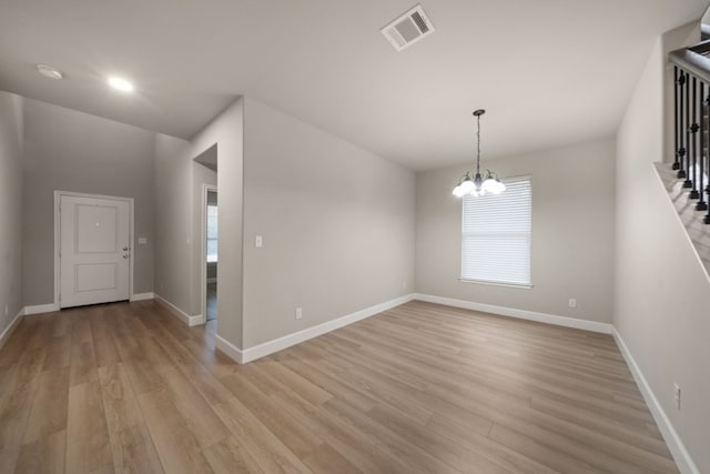 unfurnished room with a chandelier, a healthy amount of sunlight, and light hardwood / wood-style floors